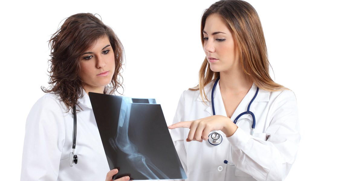 Frau im Kittel erklärt anderer Frau im Kittel ein Röntgenbild