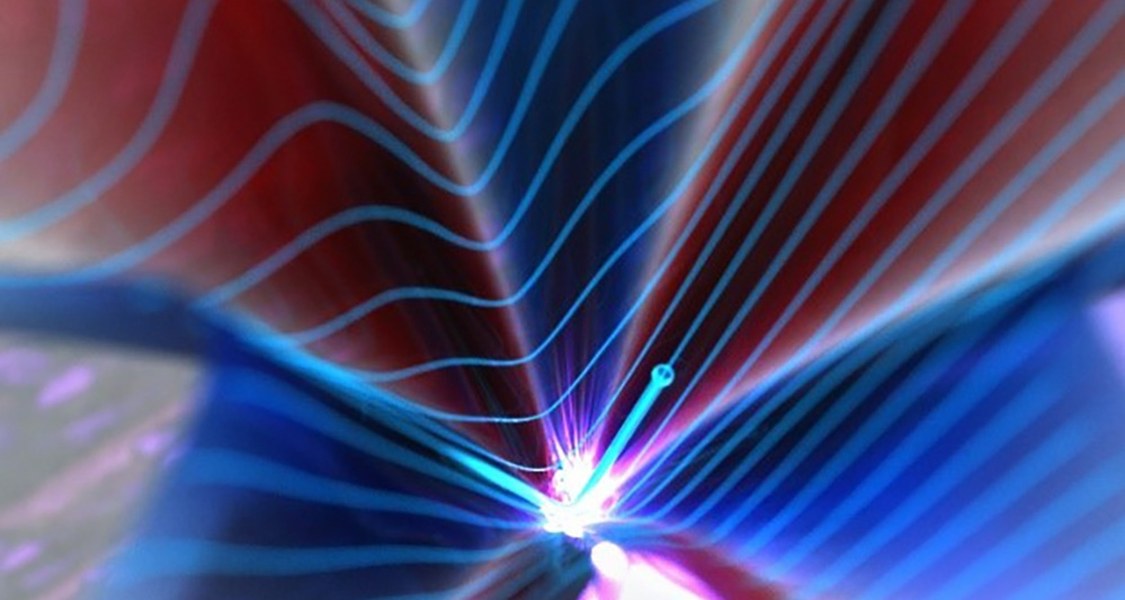 Auf der Oberfläche eines topologischen Isolators (eingefärbte Fläche) bewegen sich Elektronen (kleine blaue Kugel) mit quasi-relativistischen Geschwindigkeiten.  Durch Beschleunigung mit einer intensiven Lichtwelle können Elektronen ultraschnell durch den sogenannten Dirac-Punkt (Spitze des Kegels) beschleunigt werden. Dadurch wird die Geschwindigkeit der Elektronen abrupt umgedreht und sie bewegen sich in die gegensätzliche Richtung. Diese instantane Änderung der Geschwindigkeit führt zur Emission von breitbandiger elektromagnetischer Strahlung (Lichtblitz in der Mitte der eingefärbten Fläche). Abbildung: Brad Baxley (parttowhole.com)