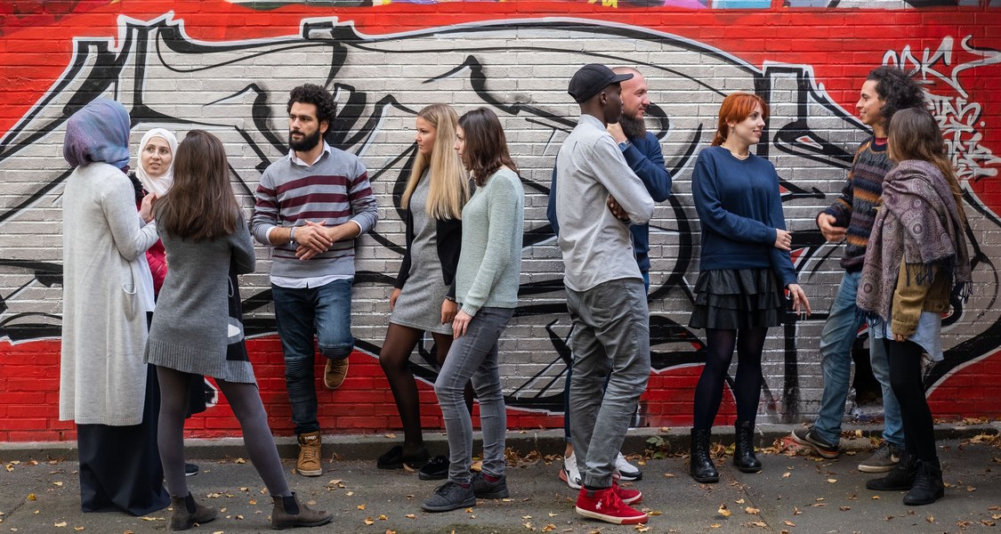 Studierende stehen vor einer Wand mit Graffiti.