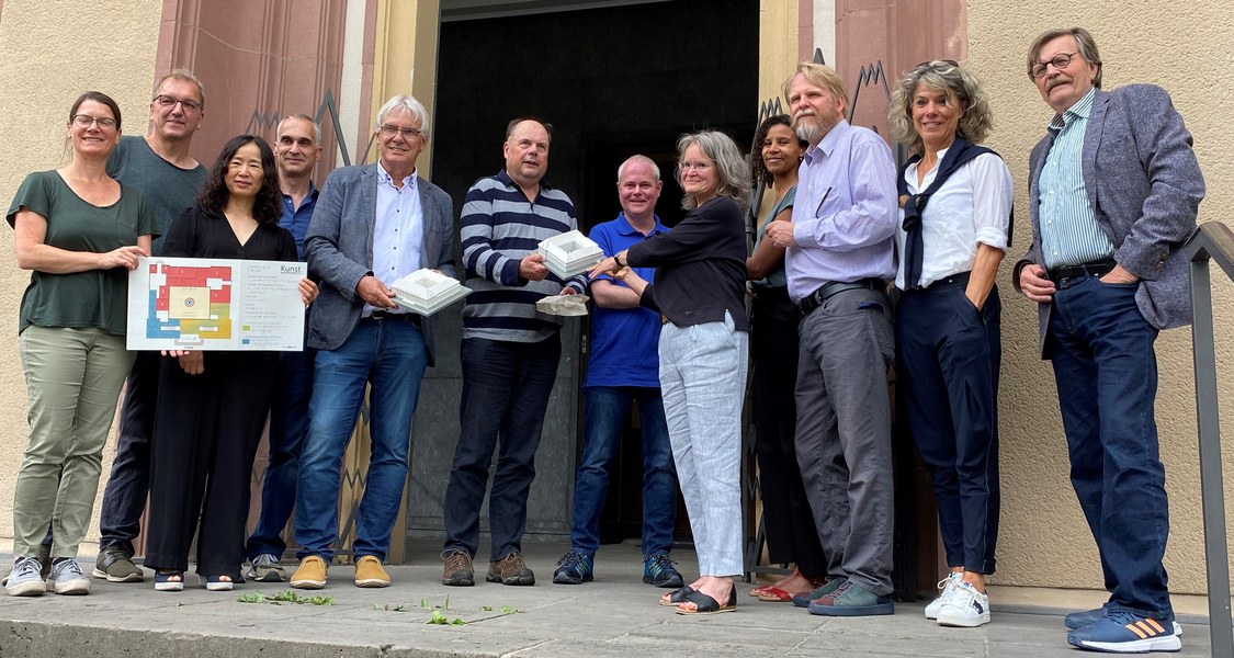 Gruppenfoto vor dem Eingang zum Museum, bei dem einzelne Personen taktile Modelle des Museums in der Hand halten