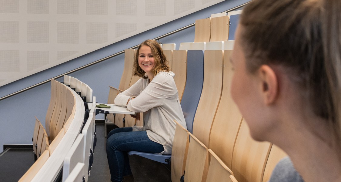 Zwei junge Frauen sitzen in einem Uni-Hörsaal