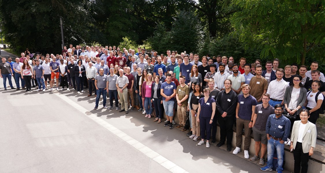 Gruppenfoto der rund 200 Teilnehmenden beim Materialforschungstag an der Universität Marburg am 15. Juni 2023. Im Hintergrund der alte botanische Garten.