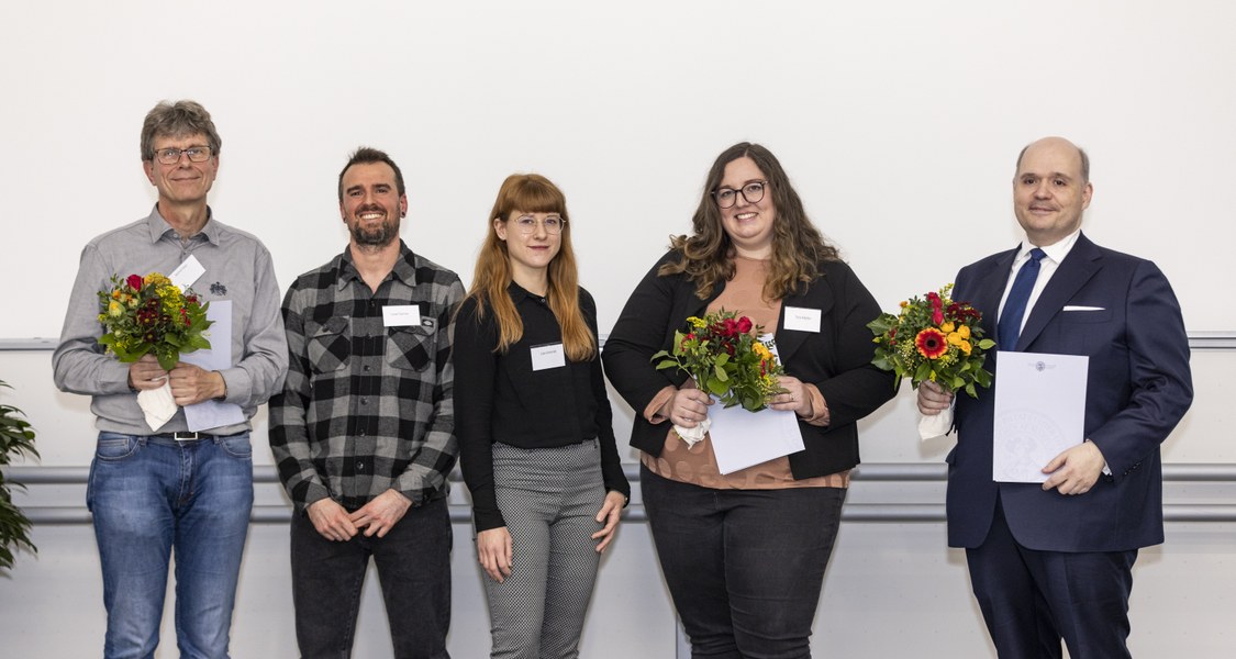 Gruppenbild von drei Männern und zwei Frauen mit Blumensträußen.