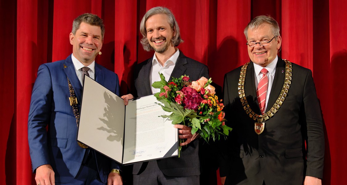 Preisträger des Marburger Kamerapreises mit Urkunde und Blumenstrauß mit zwei weiteren Personen