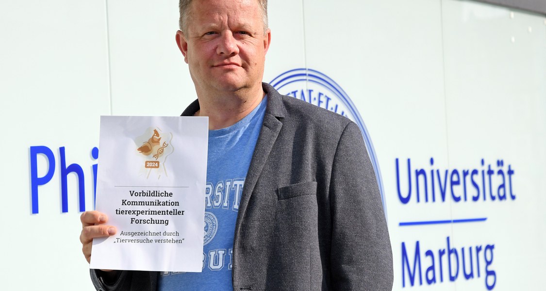 Gert Bange mit dem Siegel vor dem Uni-Verwaltungsgebäude
