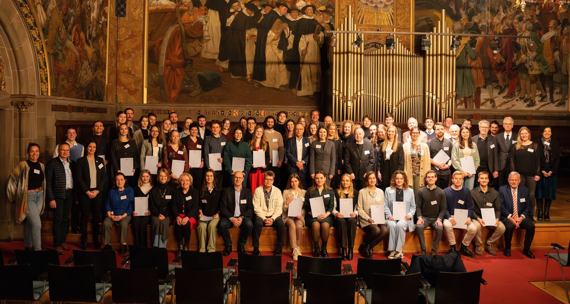 Gruppenfoto auf der Empore in der Alten Aula vor der Orgel und verschiedenen Wandgemälden