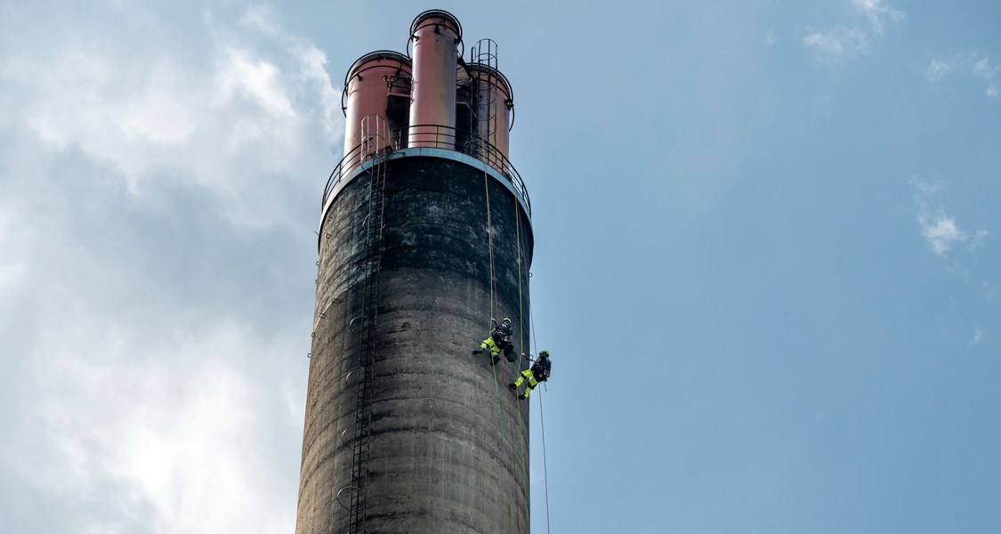 Zwei Industriekletterer seilen sich von einem Schornstein ab.