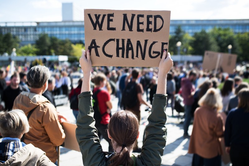 Demonstrierende halten Plakate mit der Aufschrift " we want change" in die Höhe