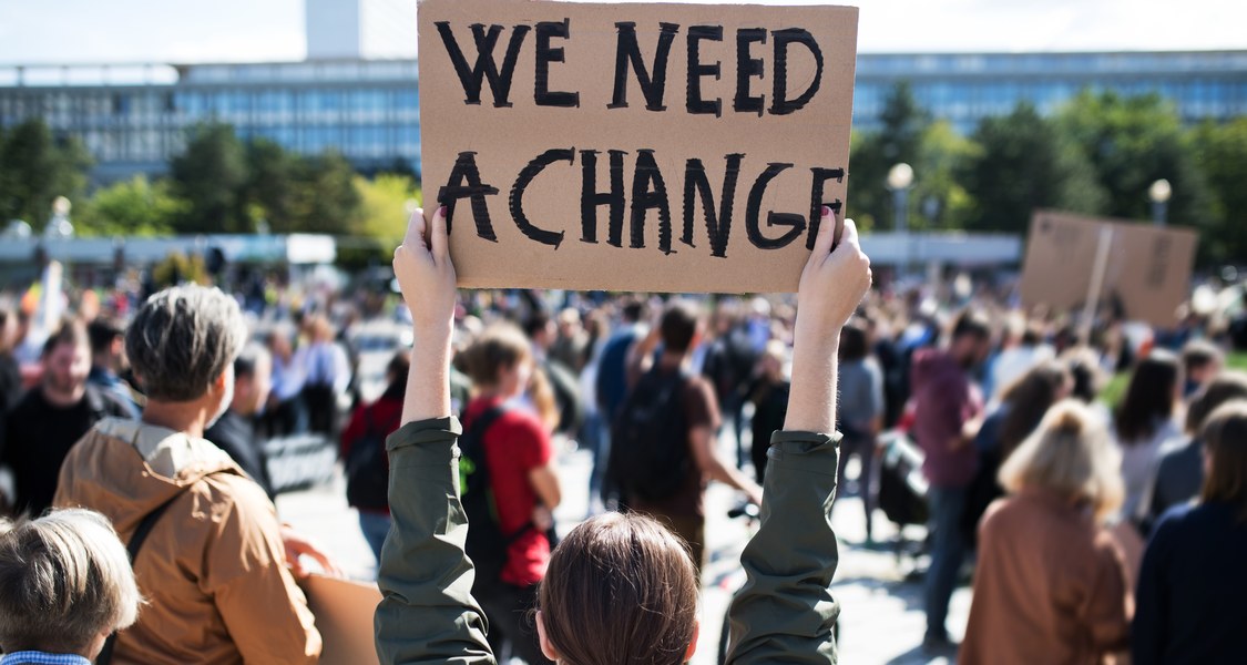 Demonstrierende halten Plakate mit der Aufschrift " we want change" in die Höhe