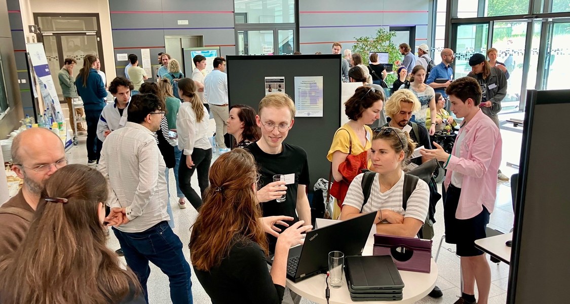 Doktorand*innen und Postdocs informierten sich im Foyer von SYNMIKRO über die Möglichkeiten von KI in Forschung und Lehre.