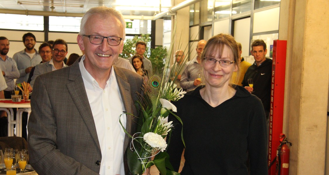 Mann links mit Blumen, Frau rechts, lachen in die Kamera