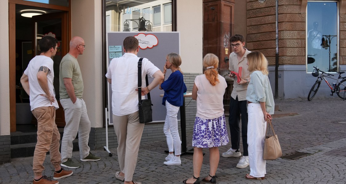 Menschen diskutieren vor Gebäude an Pin-Wänden