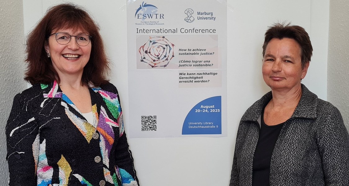 Prof. Dr. Christl Maier (links) und Prof. Dr. Angela Standhartinger mit dem Tagungsplakat.