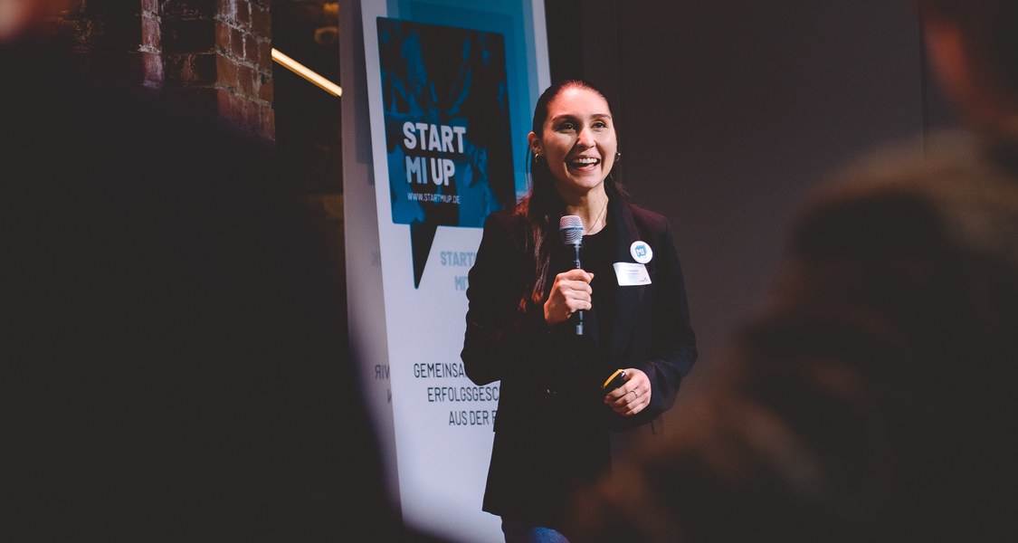 Personen bei einem Pitch auf der Bühne.