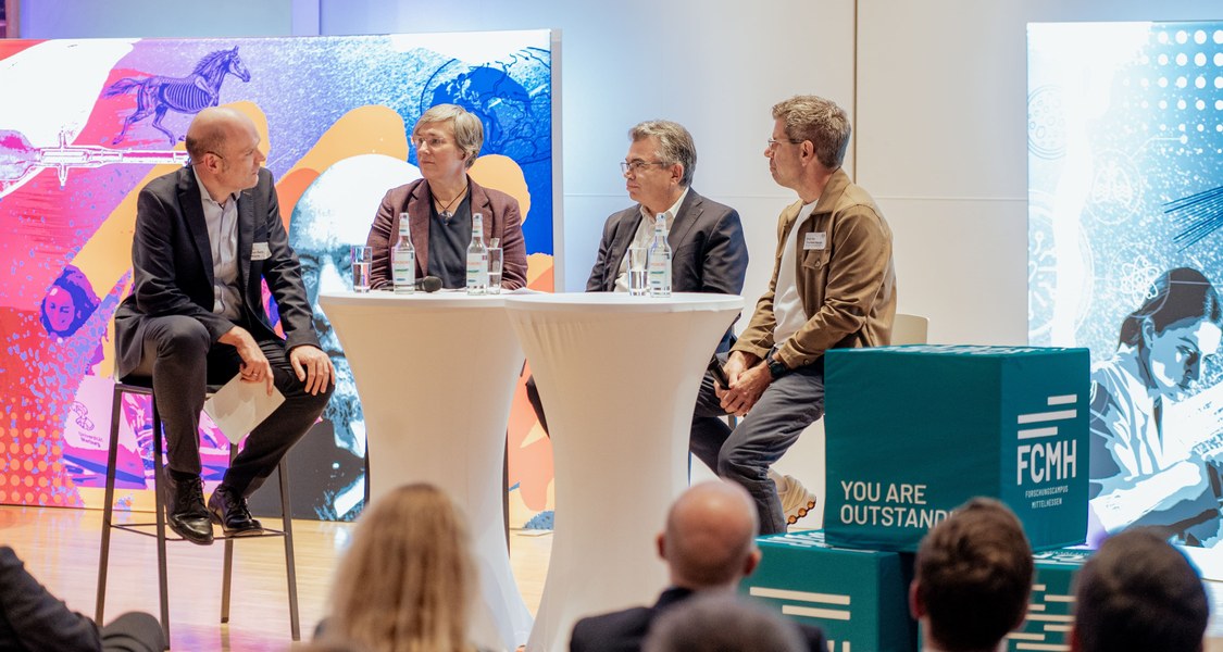 Vier Menschen auf dem Podium in einer Diskussion