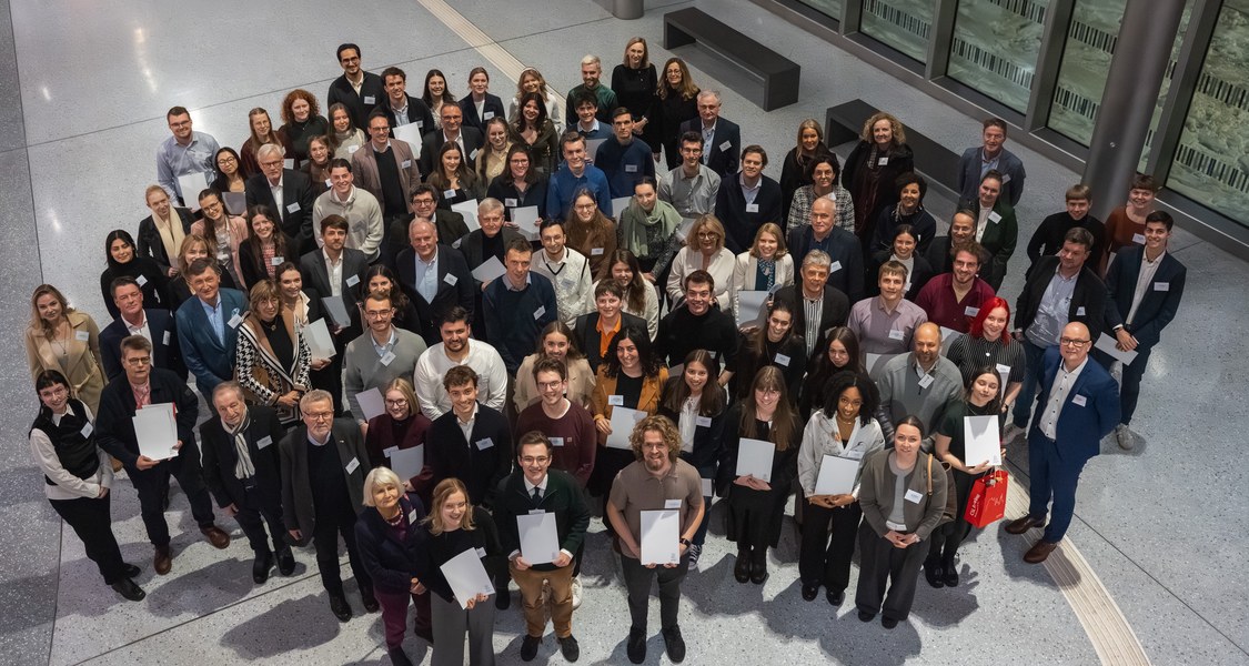 Viele Menschen in einer Gruppe von oben fotografiert. Sie halten Urkunden in den Händen