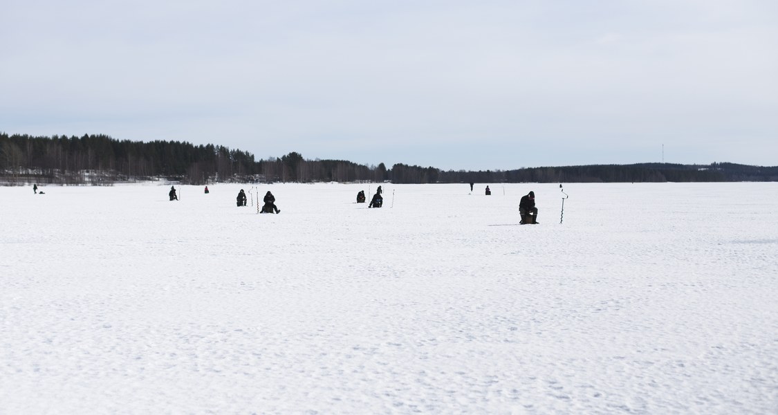 Eisfischer*innen auf einem zugefrorenen See in Finnland