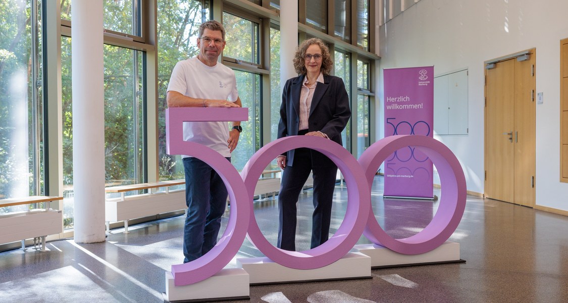 Thomas Nauss und Evelyn Korn vor einer lilafarbenen 500