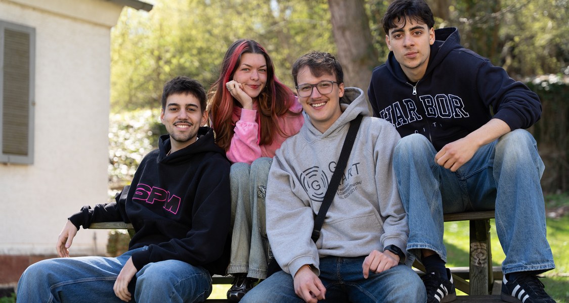 Vier junge Menschen auf einer Bank im Garten der Marburg-WG