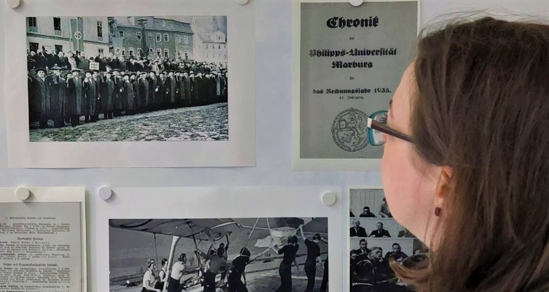 Eine Frau blickt auf historische Dokumente, die an der Wand hängen