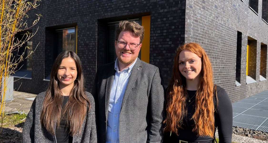 drei Menschen vor einem Gebäude