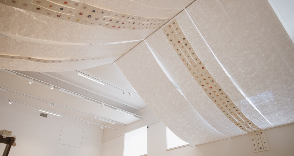 Eine Textilbahn hängt unter einer Decke. Ein Band mit Sternen läuft darüber.