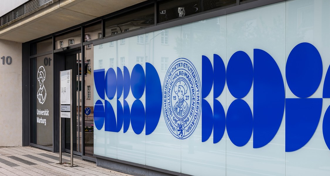 Eingang des Verwaltungsgebäudes Biegenstraße 10 mit Siegel der Universität und Logo.