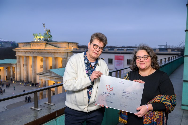 Halbtotale der beiden Personen mit dem Brandenburger Tor im Hintergrund