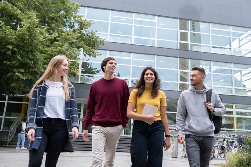 Vier Studierende vor dem Hörsaalgebäude