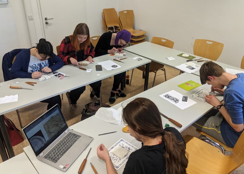 Studierenden sitzen an Tischen und bearbeiten Modellen aus Knete mit verschiedenen Werkzeugen