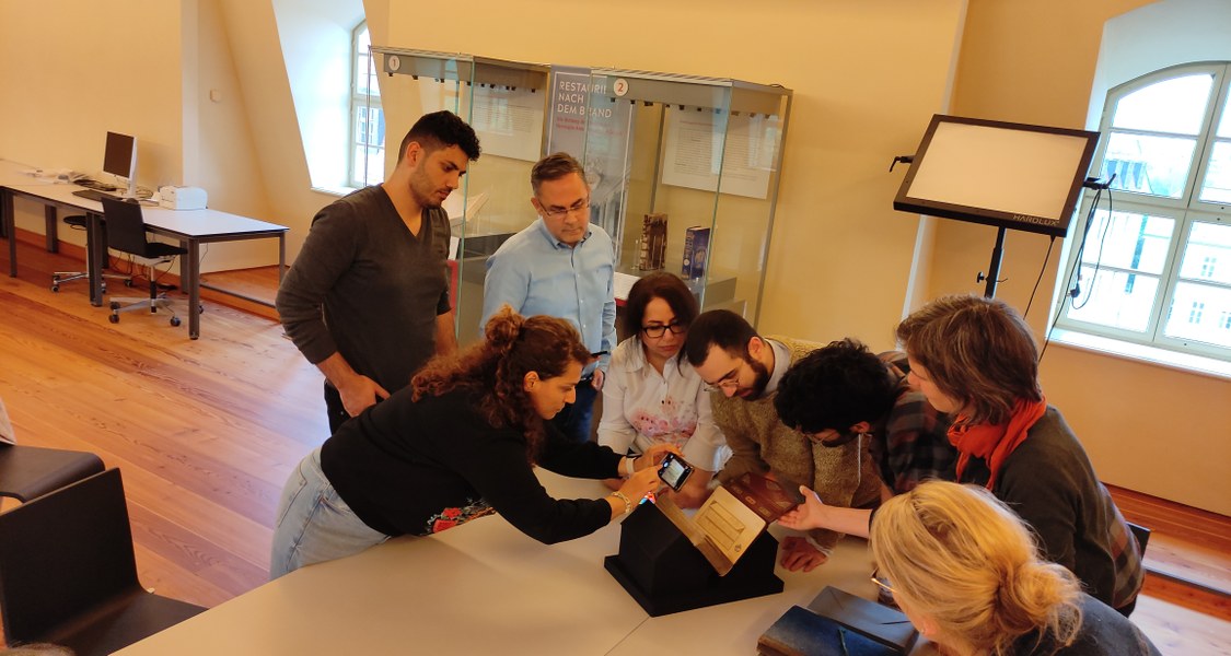 Eine Gruppe von Studierenden in Lesesaal beim Lesen von persischen Handschriften