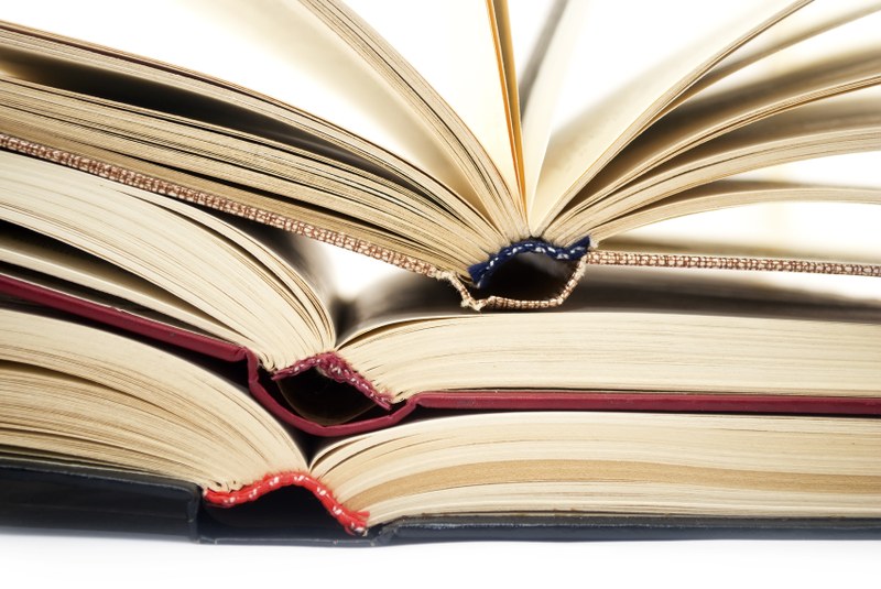 Bild von mehreren aufgeklappten Büchern übereinander.