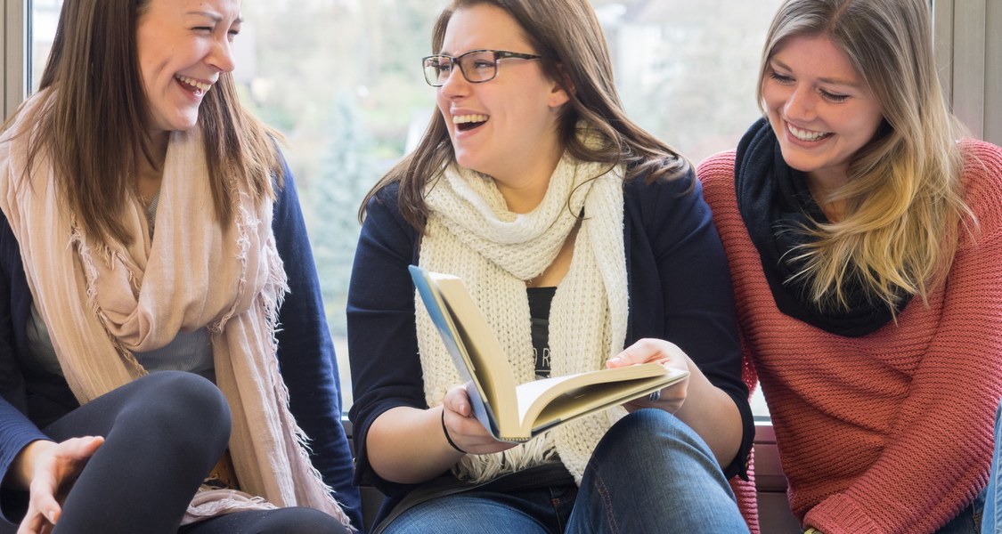 Studierende lachend mit Buch