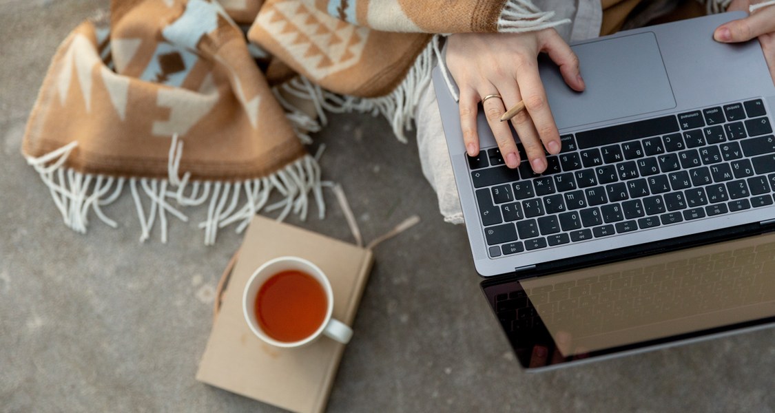 Person mit Laptop und heißem Tee