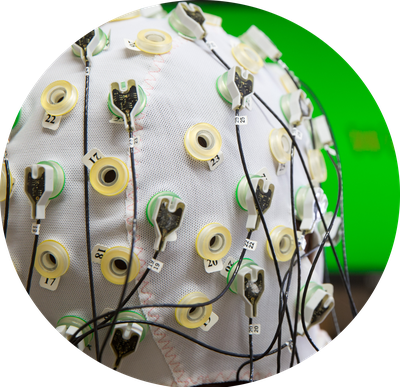 EEG Kappe mit eingesteckten Elektroden auf dem Kopf einer Person von hinten zu sehen.