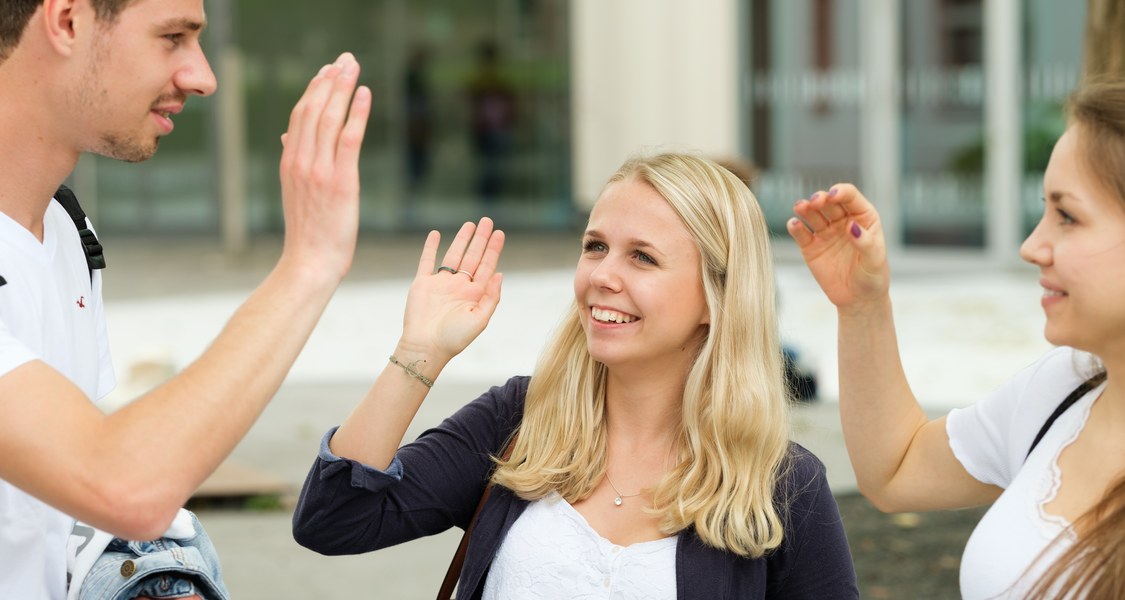 Studierende, die einander abklatschen