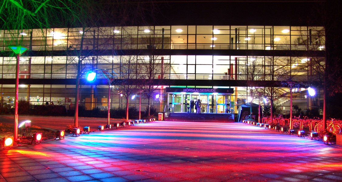 Blick auf den Haupteingang des Hörsaalgebäudes bei Nacht.
