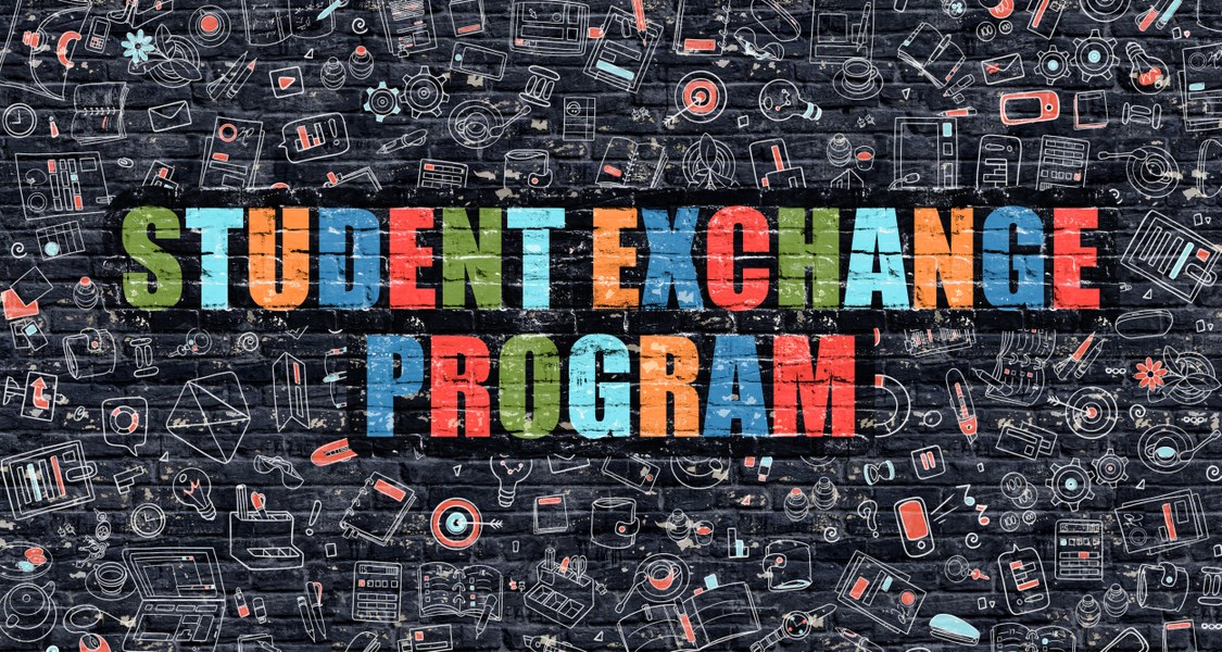 Text "Student Exchange Program" in bunten Großbuchstaben vor einer schwarzen Backsteinwand.