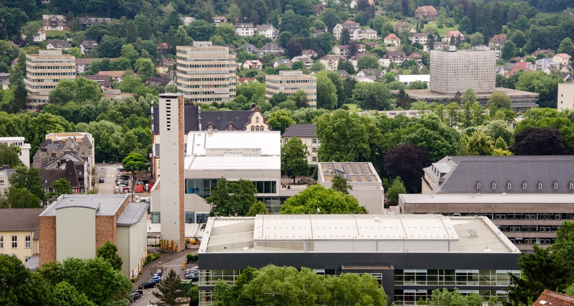 Blick über die Stadt Marburg mit dem Hörsaalgebäude und den Verwaltungsgebäuden im Vordergrund, im Hintergrund die Türme der Philosophischen Fakultät