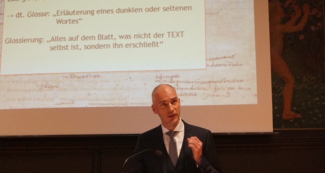 Prof. Dr. Alderik Blom bei seiner Antrittsvorlesung, im Hintergrund eine Präsentation über Glossen