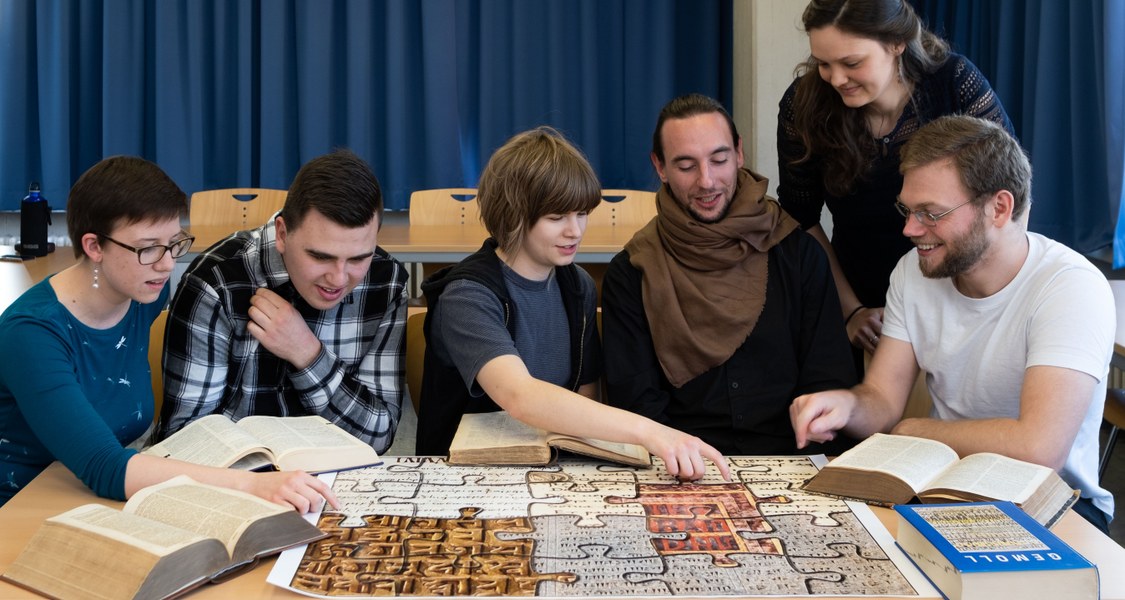 Studierende erkunden klassische Sprachen mit Sprachenpuzzle und Wörterbüchern