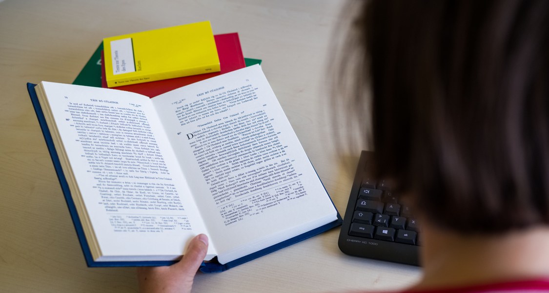 Blick über die Schulter eines Studierenden in ein offenes Buch