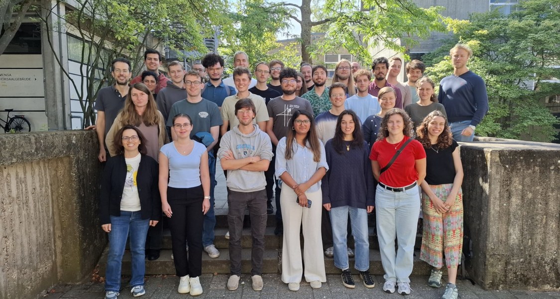Gruppenfoto der Teilnehmenden, Dozierenden und Organisierenden der Summer School vor dem Gebäude des Fachbereichs Mathematik /Group photo of the participants, lecturers, and organisers of the school in front of the Department of Mathematics