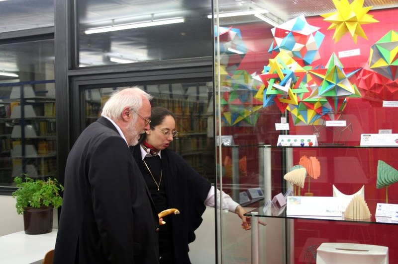 Professorien Agricola und Professor Fischer betrachten Modelle in einer Vitrine.