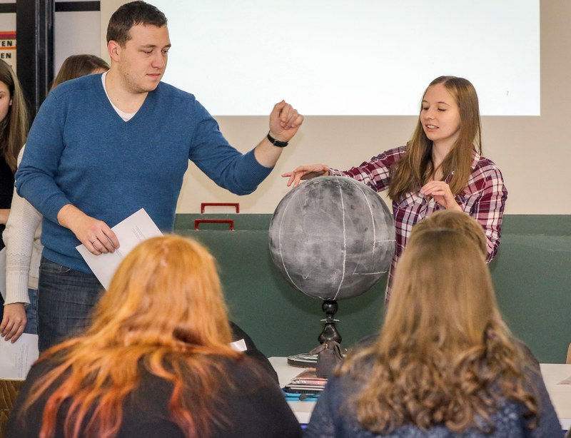 Zwei Studierende vor einem Kreideglobus.