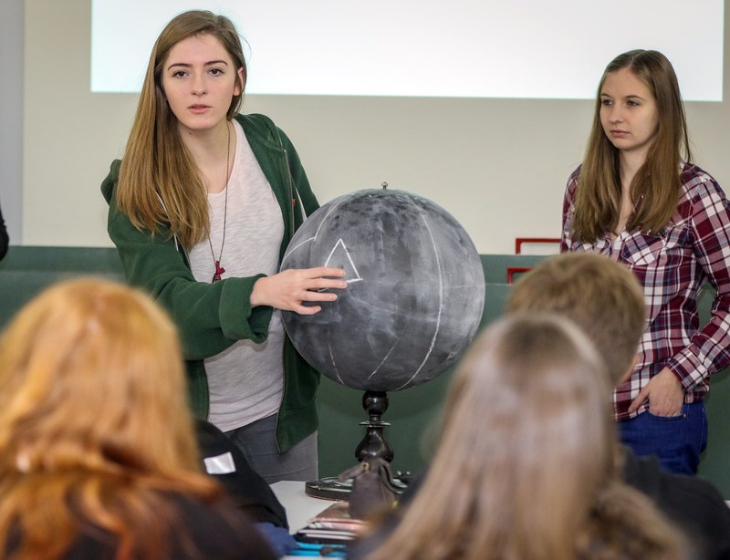 Zwei Studierende vor einem Kreideglobus.