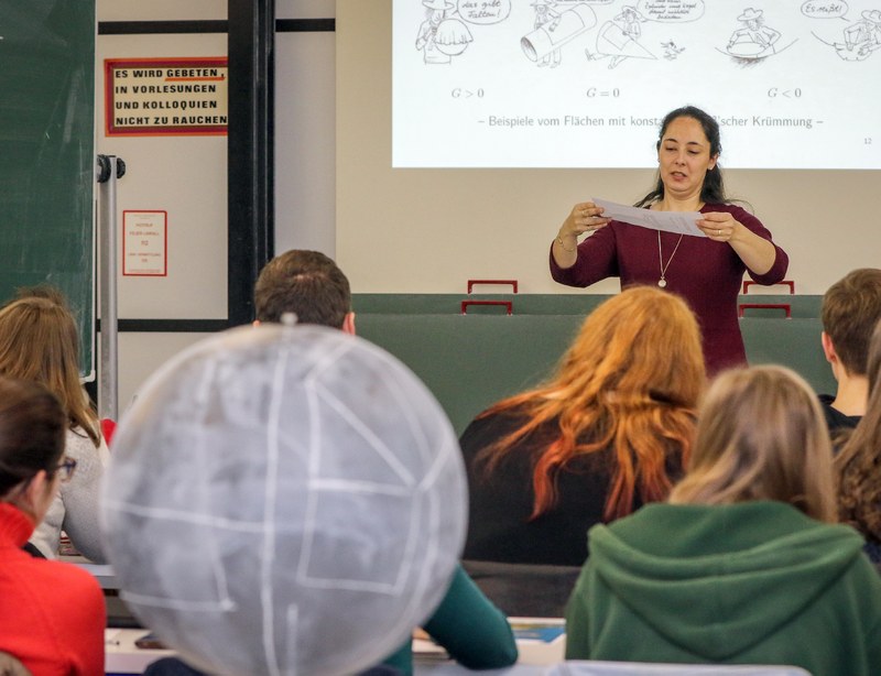 Professorin Agricola veranschaulicht die Krümmung von Flächen mit einem Blatt Papier.