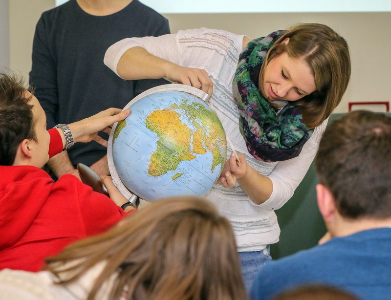 Zwei Studenten messen Distanzen auf ein Globus.