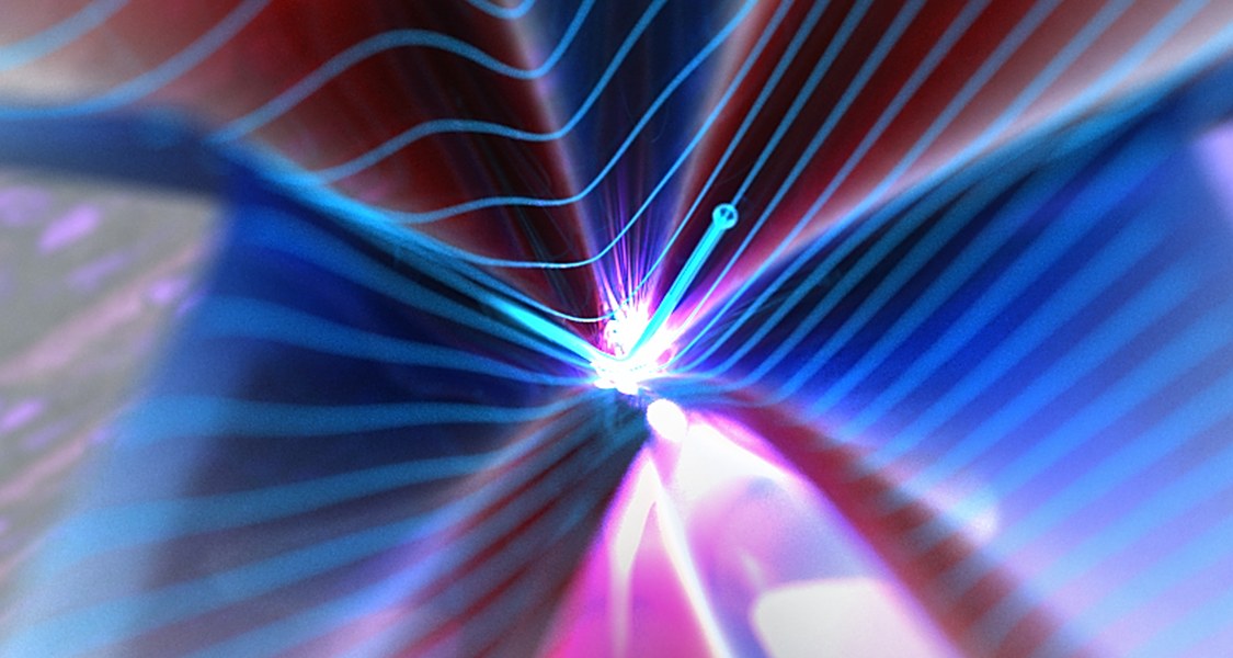 Auf der Oberfläche eines topologischen Isolators (eingefärbte Fläche) bewegen sich Elektronen (kleine blaue Kugel) mit quasi-relativistischen Geschwindigkeiten.  Durch Beschleunigung mit einer intensiven Lichtwelle können Elektronen ultraschnell durch den sogenannten Dirac-Punkt (Spitze des Kegels) beschleunigt werden. Dadurch wird die Geschwindigkeit der Elektronen abrupt umgedreht und sie bewegen sich in die gegensätzliche Richtung. Diese instantane Änderung der Geschwindigkeit führt zur Emission von breitbandiger elektromagnetischer Strahlung (Lichtblitz in der Mitte der eingefärbten Fläche).