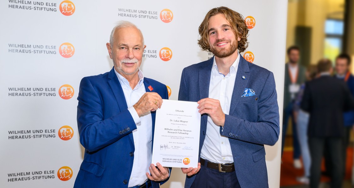 Zwei Menschen halten eine Urkunde in die Kamera